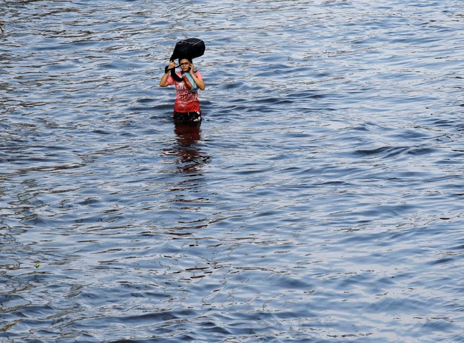 Kobieta opuszcza zalane tereny dzielnicy mieszkalnej