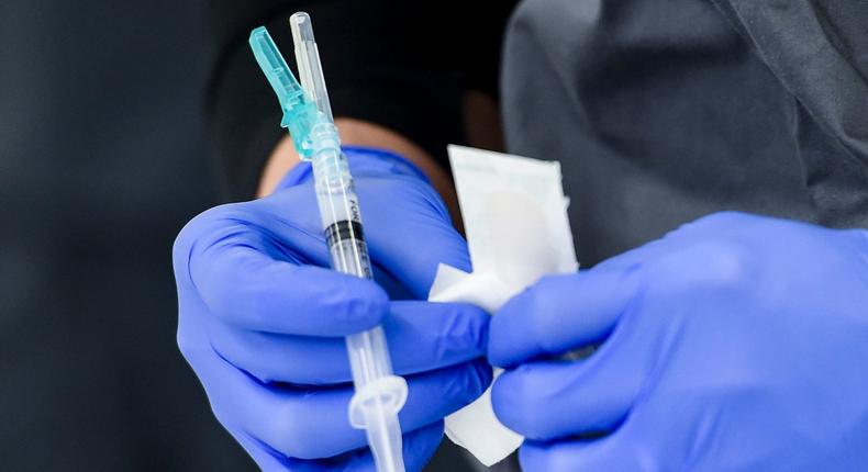A healthcare worker holds a syringe of COVID-19 vaccine.
