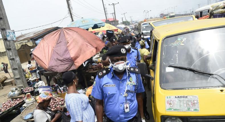 Lagos Police Commissioner Hakeem Odumosu squeezes his way through a market to monitor compliance with  measures to curb the spread of coronavirus