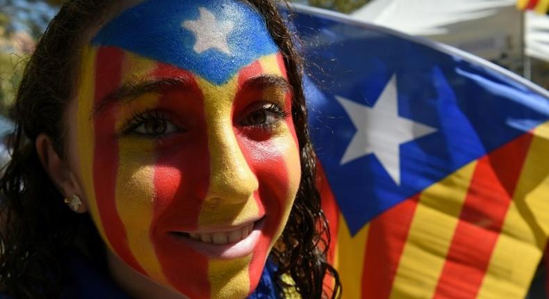 A girl with an Estelada (pro-independence Catalan flag) painted on her face smiles before a 2016 pro-independence rally in Barcelona