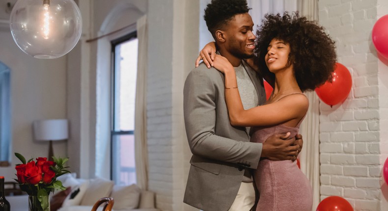 Couple dancing while hugging in a room near the table