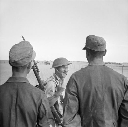 Żołnierz brytyjski pokazuje gest "V" wziętym do niewoli pod El Alamein niemieckim żołnierzom (domena publiczna).