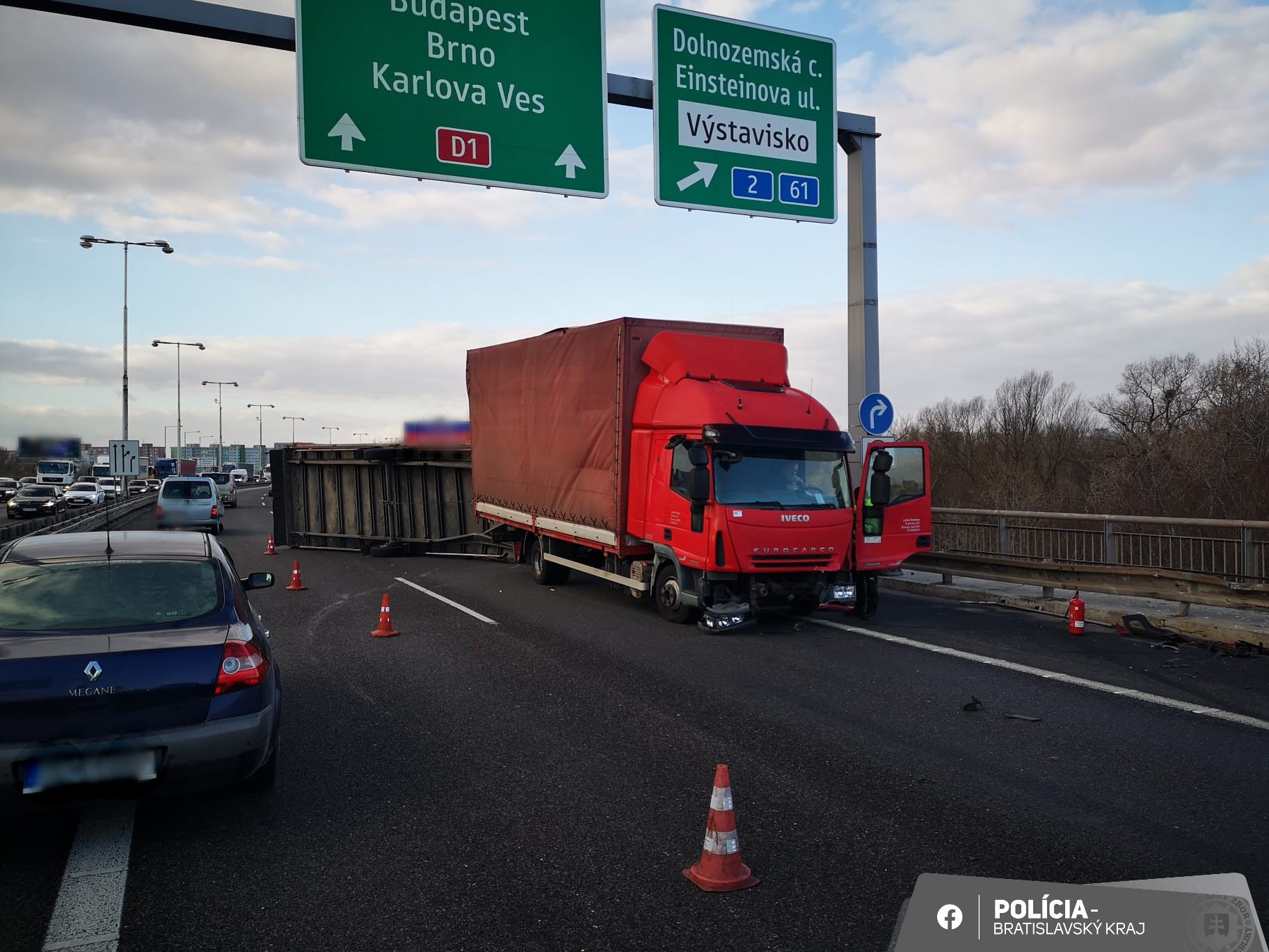 Policajti na Prístavnom moste odstraňujú prevrátený prívesný vozík za dodávkou.