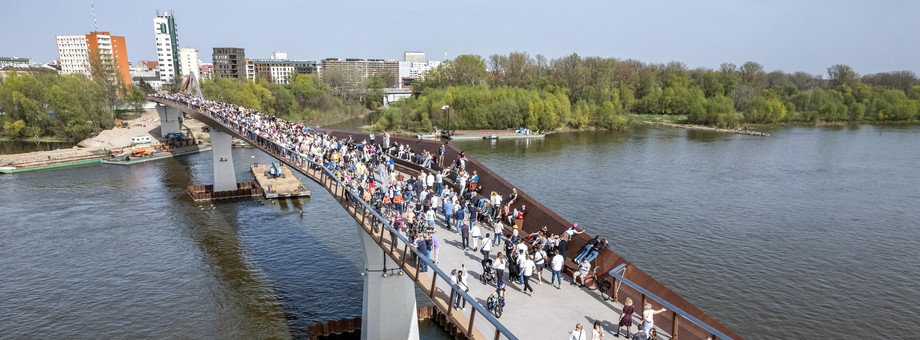 „Trwa szaleństwo związane z odwiedzaniem i przechadzaniem się przez nową kładkę pieszo-rowerową przerzuconą przez Wisłę, która ostatecznie kosztowała ok. 154 mln zł – wobec planowanych pierwotnie 121 mln zł”.