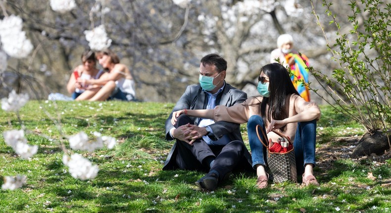 A couple wearing masks sits under blooming Japanese Cherry Blossom trees in Central Park amid the coronavirus pandemic on April 08, 2021 in New York City.
