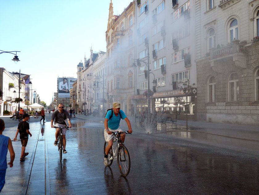 rowerzyści przejeżdżają pod kurtyną wodną