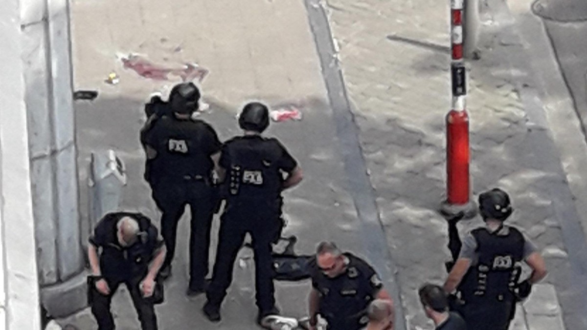 Police special forces are seen next to a man lying on the pavement and who supposedly was the shooter during a shooting in Liege