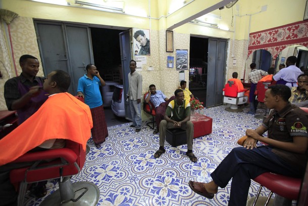 Men receive haircuts at a barber shop in Mogadishu October 3, 2013. Street lamps now brighten some o