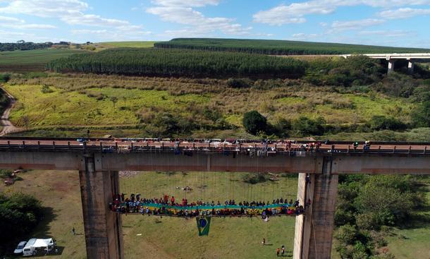 People eat at a barbecue as they sit on a table while suspended under a bridge using rapelling techn