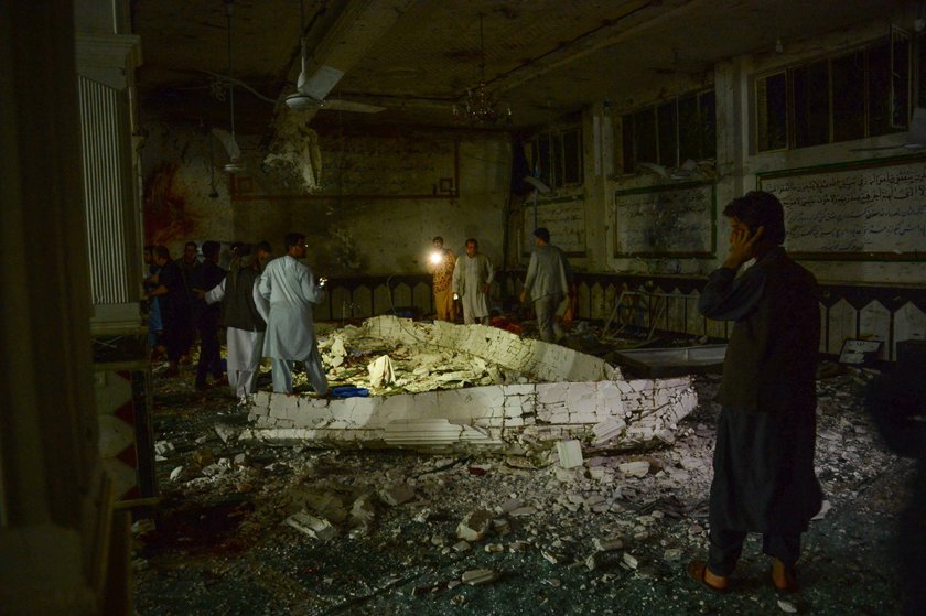 Afghan policemen and relatives inspect at the site of a suicide attack in Herat, Afghanistan