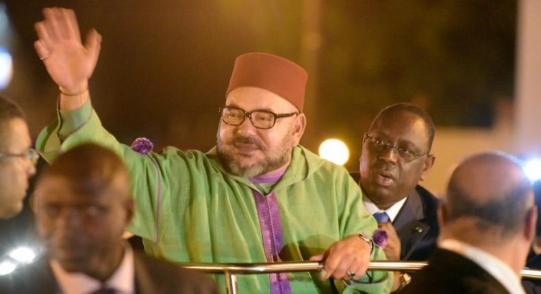 Moroccan King Mohammed VI (C) waves to the crowd eyed by Senegalese president Macky Sall upon his arrival at Dakar's airport on November 6, 2016