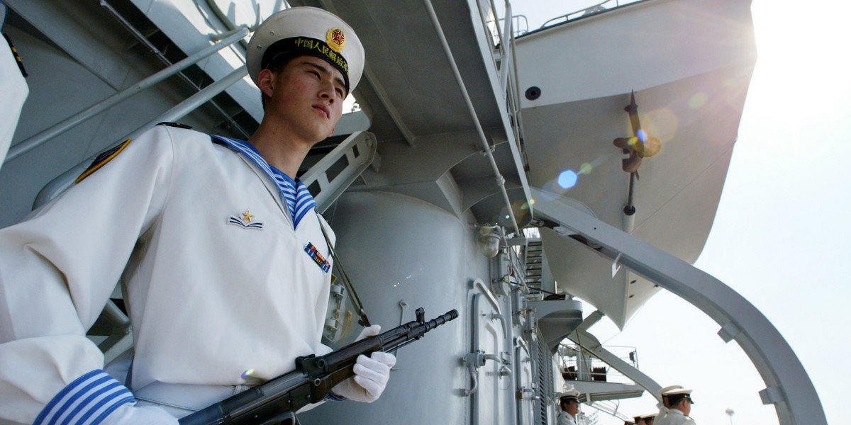 A sailor stands guard onboard the Chinese warship Qingdao in Qingdao, China, September 23, 2002.