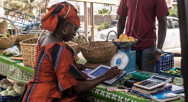 Une femme sur un marché de Dakar traite une commande de légumes à l’aide de sa tablette Weebi © Vincent Tremeau - La Banque mondiale