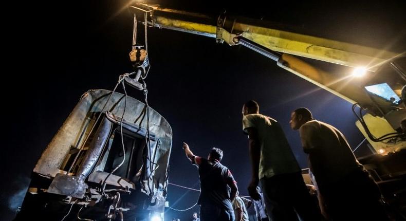 Emergency personnel lift a carriage with a crane following a collision between two trains on August 11, 2017 near the Mediterranean city of Alexandria that killed at least 40 people