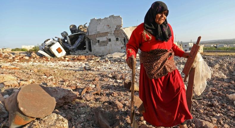 A woman salvages items from a building reportedly destroyed by an air strike on the Syrian town of Kafranbel in Idlib province on May 20, 2019