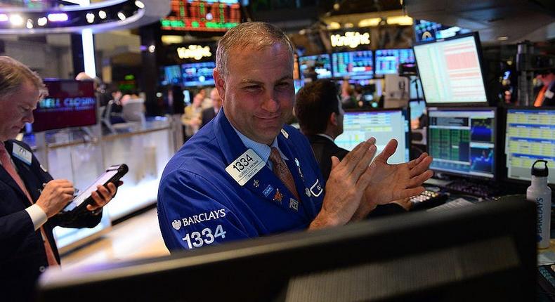 A stock trader claps at the end of trade at the New York Stock Exchange