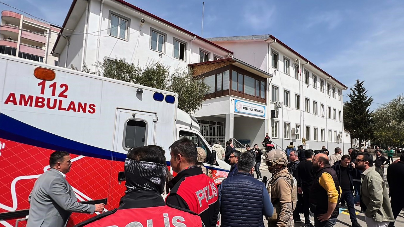 Turecké bezpečnostné sily a záchranári stoja na nádvorí strednej školy, kde útočník spustil paľbu v Kahramanmarasi.