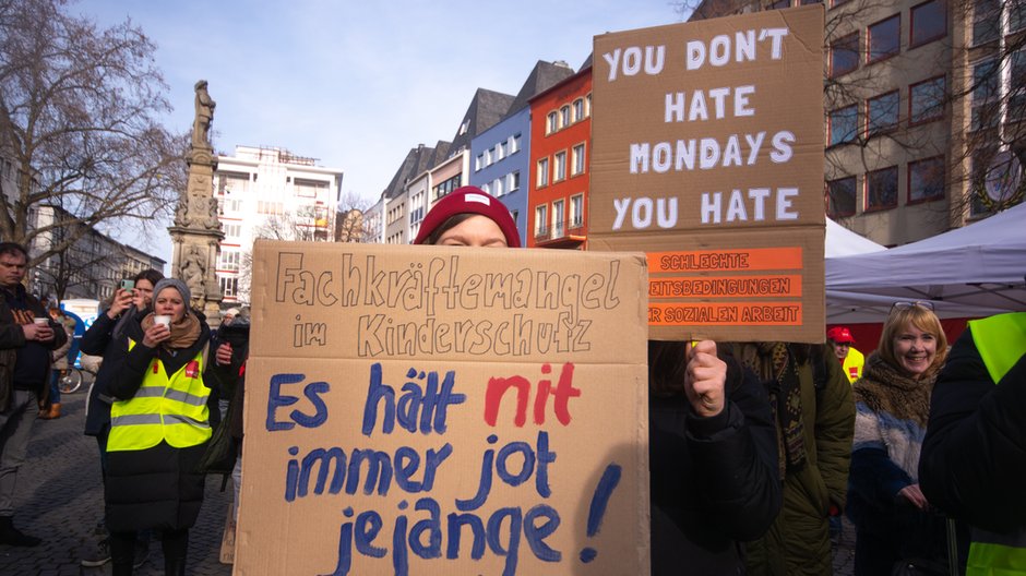 Protestujący trzymający znaki podczas wiecu zorganizowanego przez związek zawodowy Verdi dla pracowników sektora publicznego, aby domagać się lepszych płac podczas strajku w Kolonii, 9 lutego 2023 r.