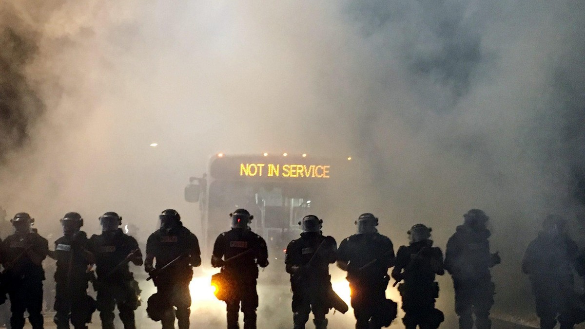 Police officers wearing riot gear block a road during protests after police fatally shot a man in the parking lot of an apartment complex in Charlotte