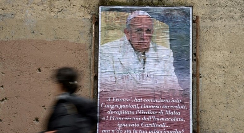 A woman walks past an anti-Pope Francis poster featuring a portrait of the pontiff and a critical message ending Where's your mercy? in central Rome on February 6, 2017