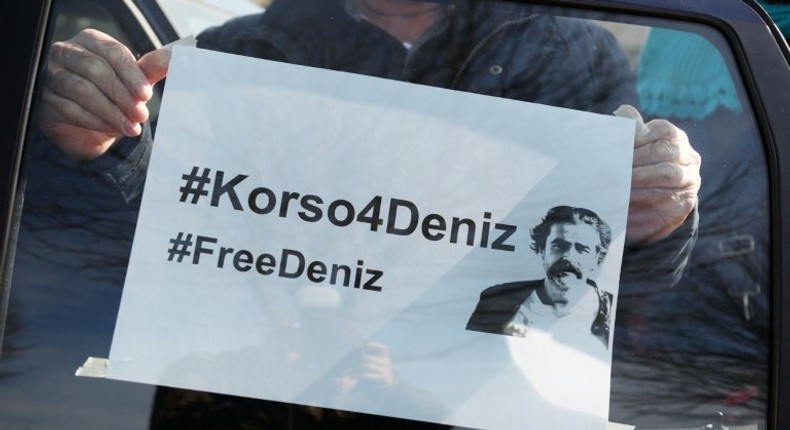 A demonstrator sticks a poster reading #FreeDeniz on a car window as he takes part on February 25, 2017 in Floersheim near Frankfurt am Main, western Germany, in a protest to support journalist Deniz Yucel detained in Turkey