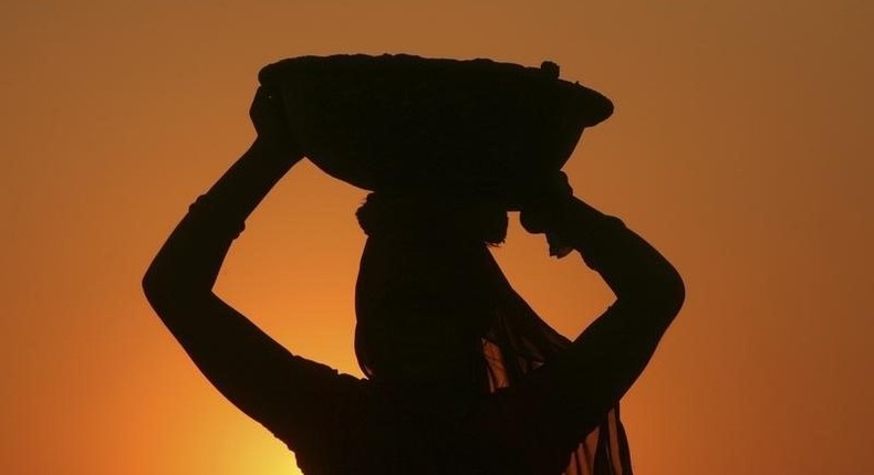 A woman labourer carrying cement is silhouetted against the setting sun at the site of a commercial complex on the outskirts of Jammu November 22, 2012. 