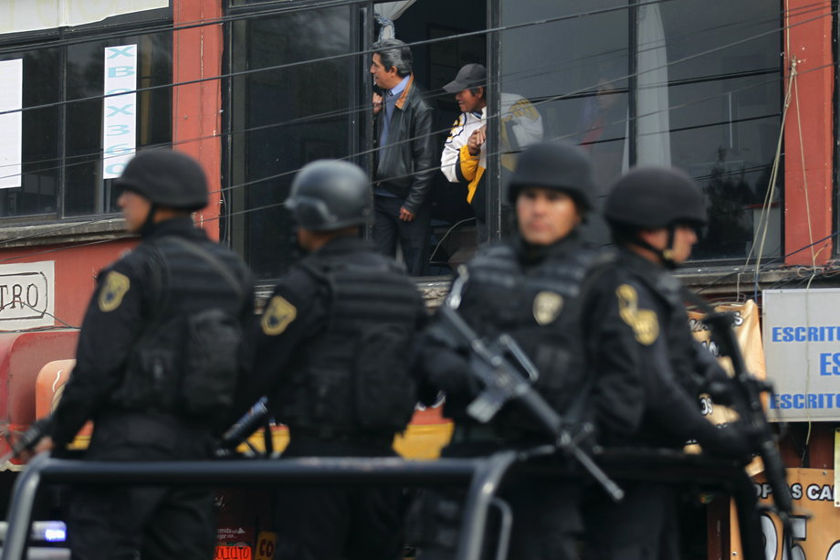 Residents look on as policemen patrol during a joint security operation in Ecatepec, on the outskirts of Mexico City, January 22, 2013.