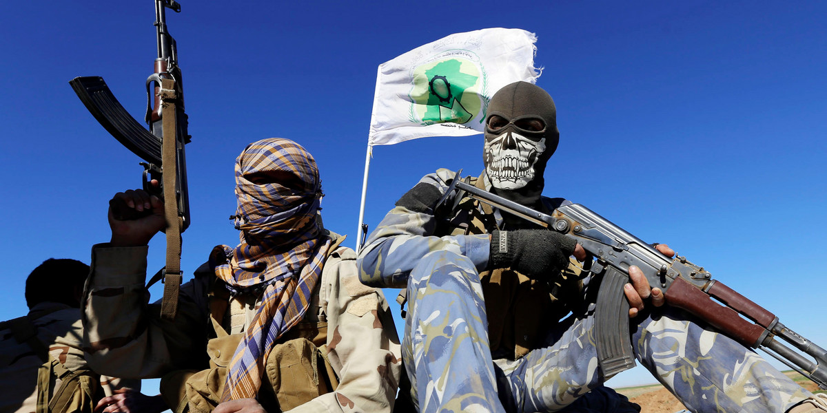 Masked Shi'ite fighters hold their weapons in Al Hadidiya, south of Tikrit, en route to the Islamic State-controlled al-Alam town, where they are prepared to launch an offensive, March 6, 2015.