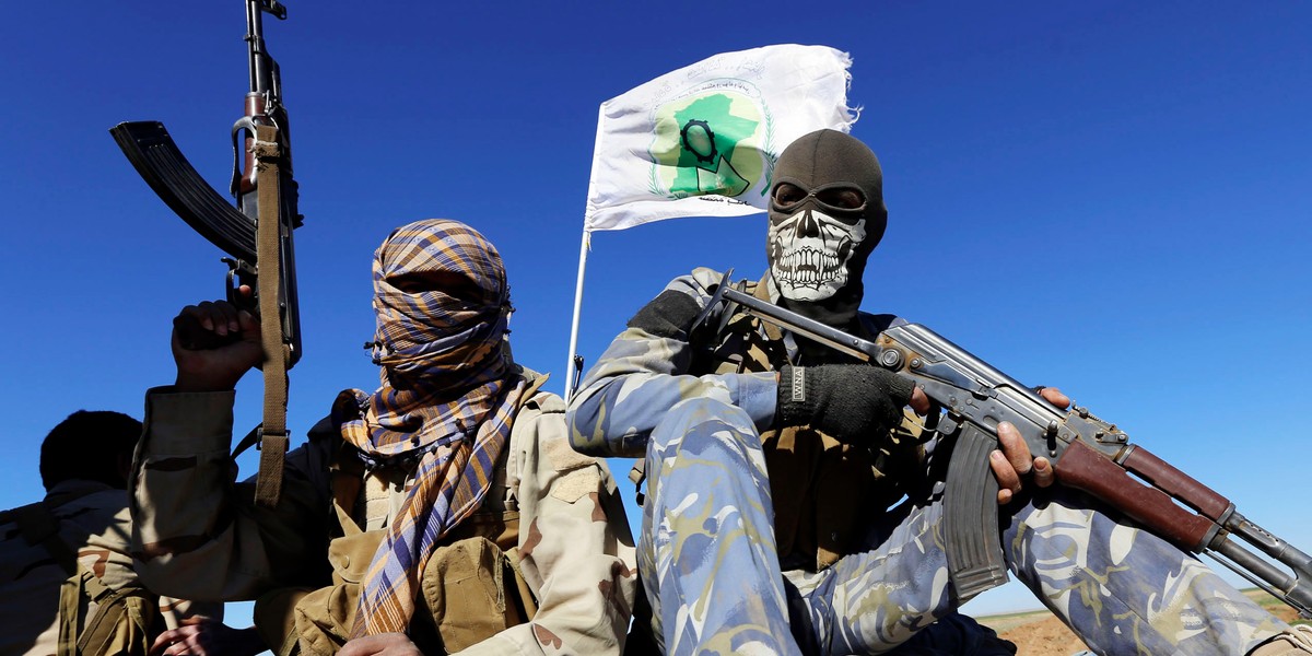 Masked Shi'ite fighters hold their weapons in Al Hadidiya, south of Tikrit, en route to the Islamic State-controlled al-Alam town, where they are prepared to launch an offensive, March 6, 2015.