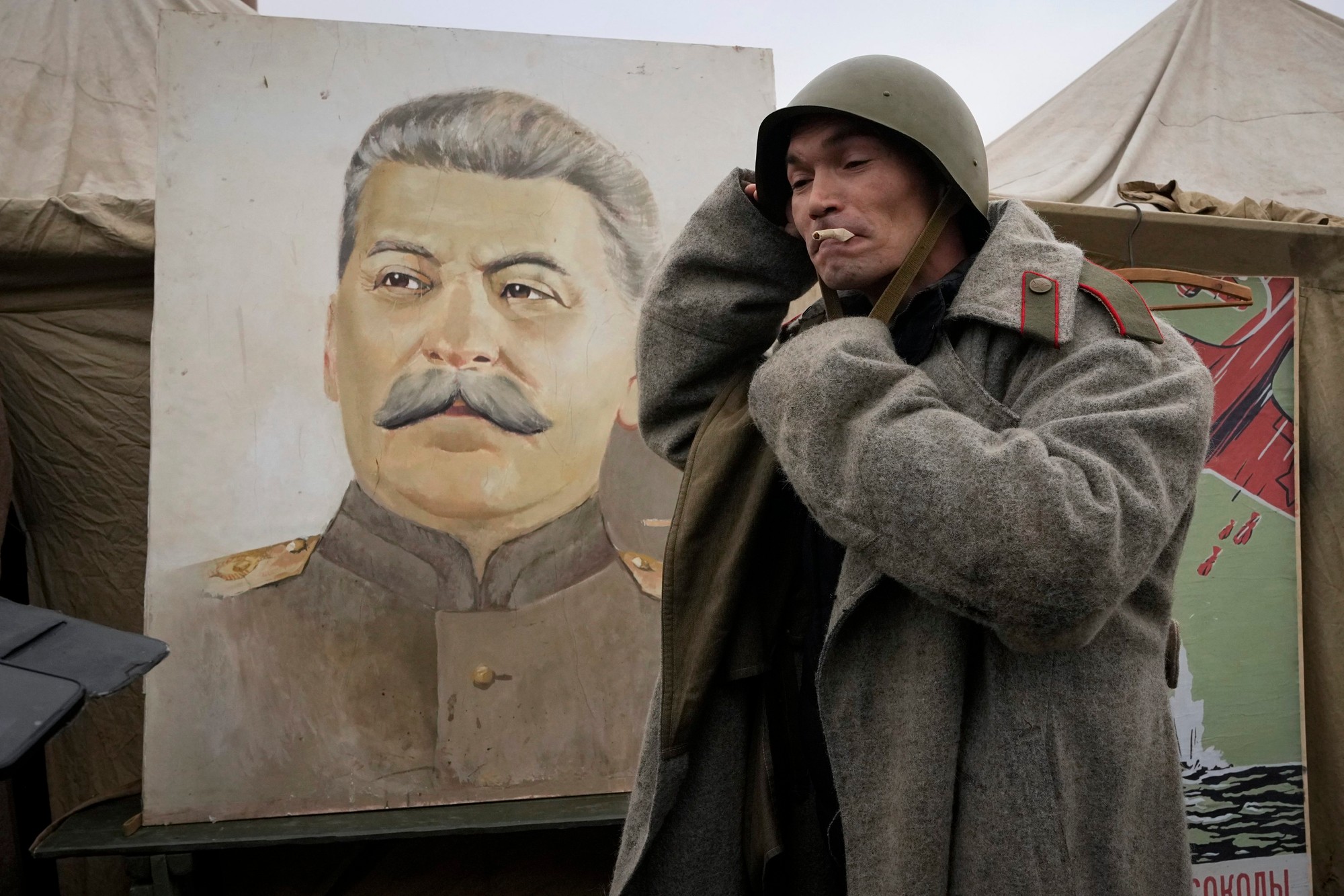 Muž má na sebe uniformu sovietskej armády z obdobia druhej svetovej vojny blízko portrétu sovietskeho diktátora Josefa Stalina na vojensko-historickej výstave v Petrohrade.