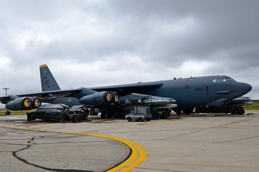 B-52H podczas uzbrajania w pociski AGM-86B. Zwraca uwagę wózek najbardziej po lewej, na którym umieszczono obrotowy mechanizm z zamocowanym pakietem pocisków przeznaczonych do umieszczenia w komorze bombowej.