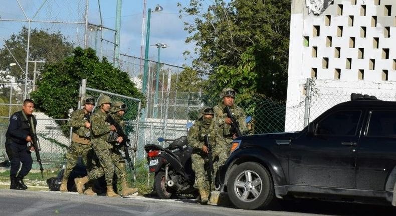 Police and soldiers take cover during an attack by gunmen on the Quintana Roo state prosecutor's office in Cancun, Mexico, which left four people dead