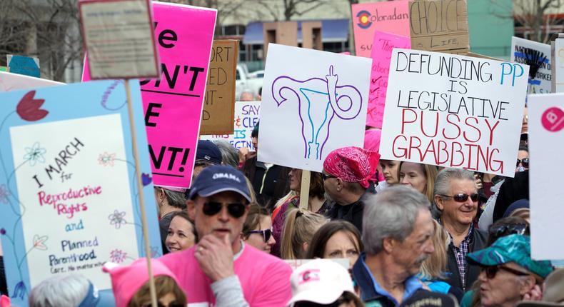 Planned Parenthood supporters hold signs at a protest in downtown Denver on February 11, 2017.