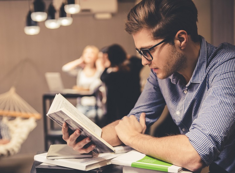 młody mężczyzna, student czyta dokumenty, książki, nauka