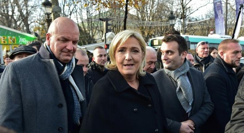 French far-right Front National party president,and candidate for France's 2017 presidential election, Marine Le Pen (C) walks along with FN vice-president Florian Philippot (R) during a visit of a Christmas market in Paris on December 8, 2016