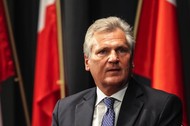 Aleksander Kwaśniewski na tle polskiej flagi