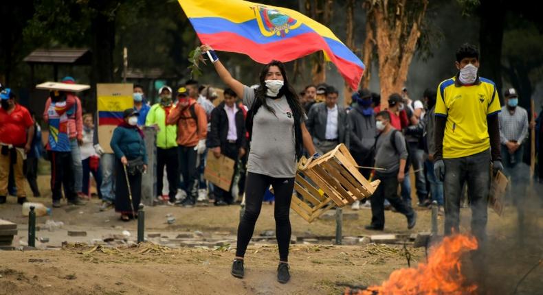 A demonstrator waves an Ecuadoran flag during clashes with riot police amid protests over a fuel price hike ordered by the government to secure an IMF loan on October 12, 2019