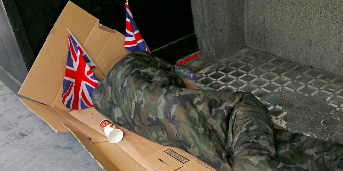 A homeless person lays on cardboard decorated with Union Flags in central London June 3, 2012.