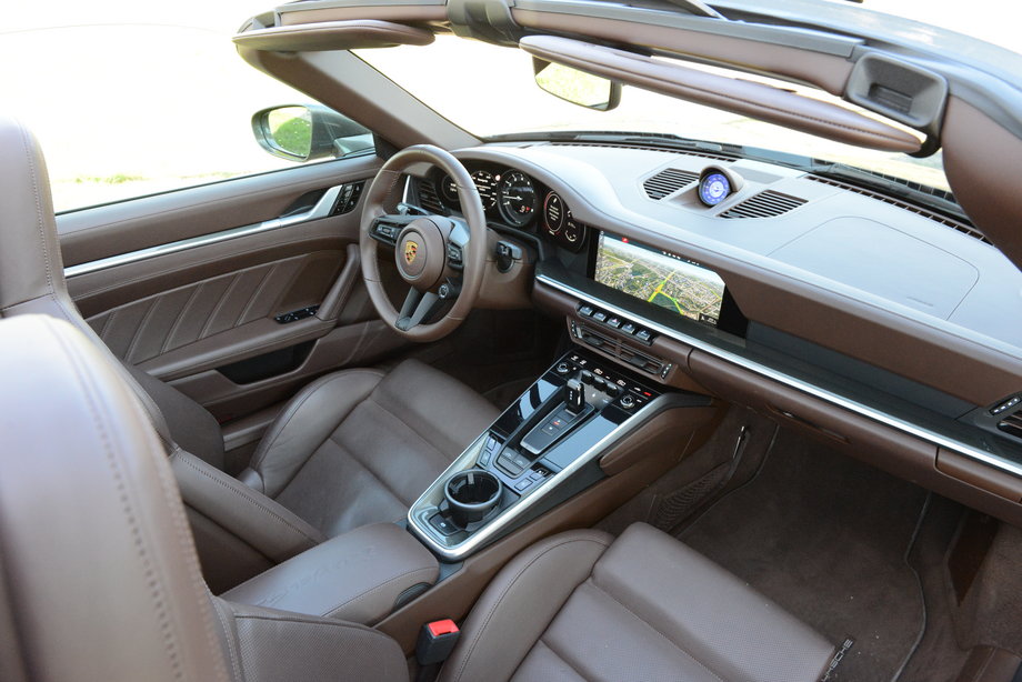 Porsche 911 Targa 4S ma nowoczesne wnętrze z wielkimi ekranami i cyfrowymi wskaźnikami. Nie brak jednak smaczków jak centralny obrotomierz lub stacyjka po lewej stronie.
