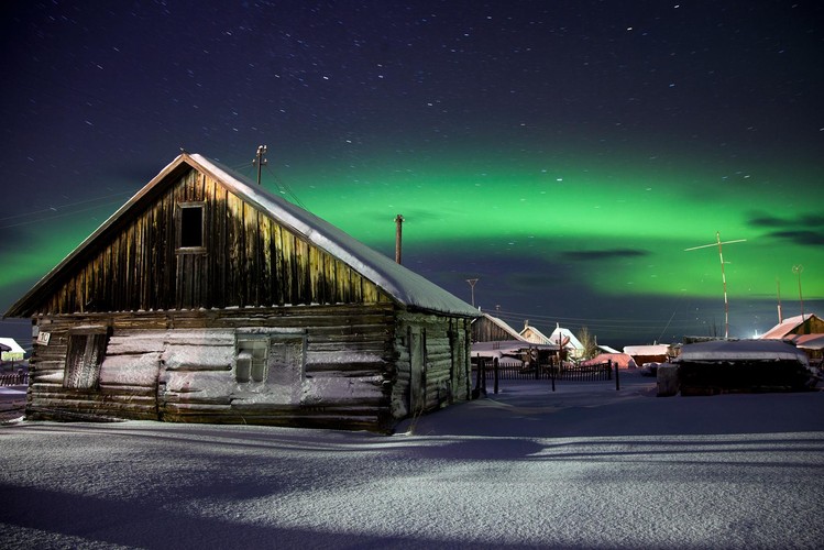 Zorza polarna rozbłyskuje nad starą, opuszczoną częścią wioski Łowoziero, leżącą na Półwyspie Kołymskim. Wszyscy mieszkańcy wioski przenieśli się do betonowych bloków. Fotografia Tomka Goli otrzymała drugie miejsce za zdjęcie pojedyncze w kategorii 