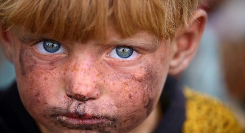 A displaced Syrian child, who fled the area surrounding the Islamic State group stronghold of Raqa, is photographed at a temporary camp in the village of Ain Issa