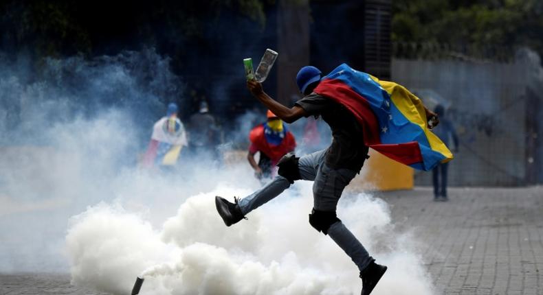 A protester kicks back a tear gas canister fired by security forces on opposition marchers in Caracas