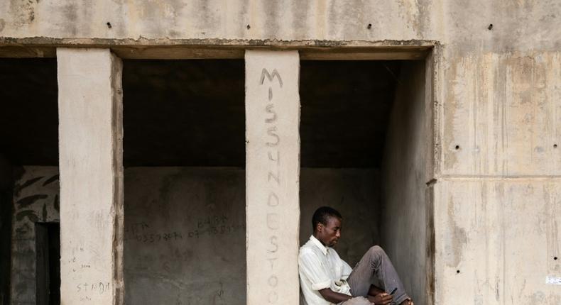 A man pages through his mobile phone while sitting at the Mohammed Goni Stadium internally displaced camp in Maiduguri, northeast Nigeria on July 26, 2019. Sixty-five people were killed and more wounded when Boko Haram fighters raided a camp for people displaced by the jihadist conflict outside Maiduguri,officials said