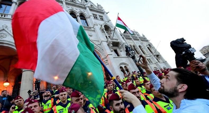 People protest as police officers stand guard in front of the parliament building in Budapest on April 4, 2017