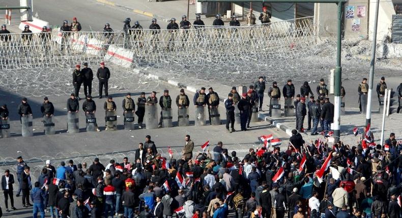 Iraqi security forces stand guard as supporters of the Sadrist movement gather during a demonstration in Baghdad's Tahrir Square on February 11, 2017, to demand the formation of an independent electoral commission