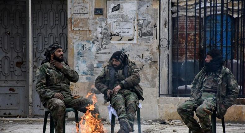 Syrians soldiers sit by a fire in the former rebel-held Ansari district of Aleppo, on December 23, 2016