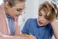 Private tutoring lesson for 10 years old blonde primary school boy while doing his homework together with female tutor in her twenties.