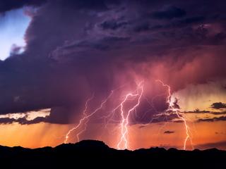 Lightning bolts strike from a sunset storm
