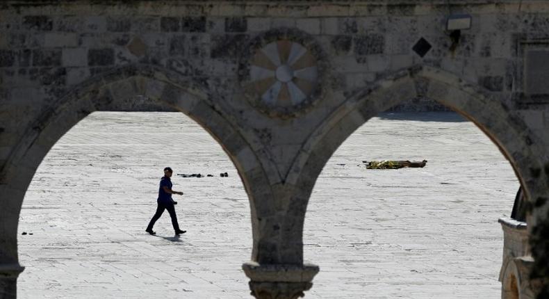 An Israeli policeman walks past a body at the Al-Aqsa mosque compound following an attack on security forces in Jerusalem's Old City on July 14, 2017