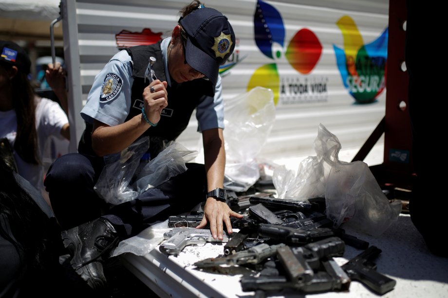 A police officer hammers a pistol during an exercise to destroy seized weapons in Caracas, Venezuela, August 17, 2016.